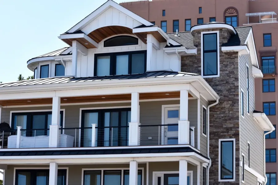 Multi-story coastal home with stone accents, metal roof and seamless gutters in Ventnor, NJ
