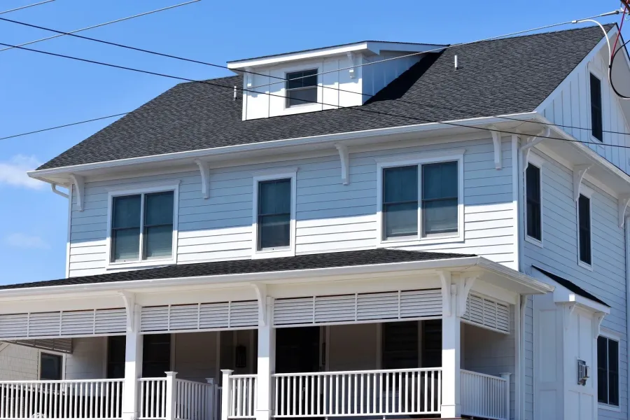 Blue clapboard home with white seamless gutters above a covered front porch in Ventnor, NJ