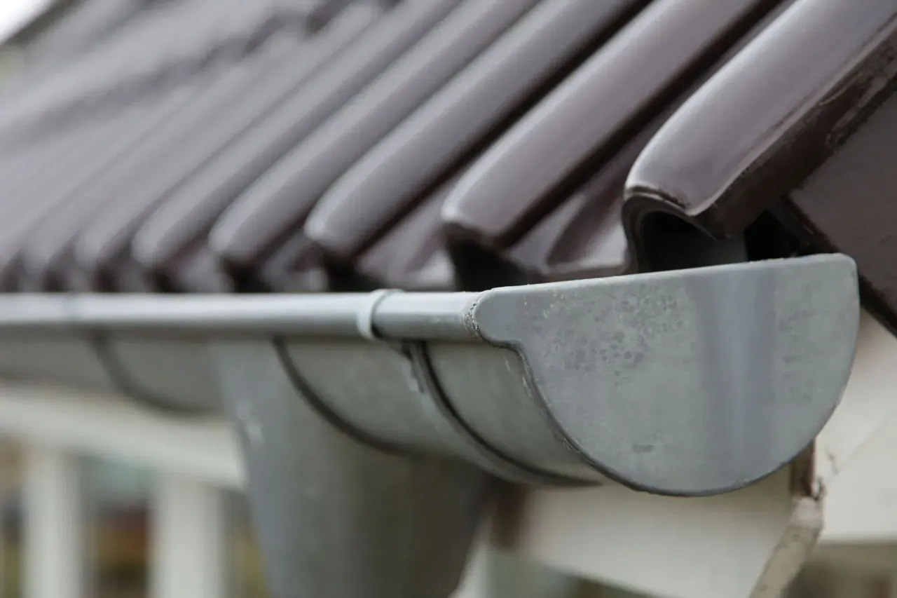 Weathered galvanized half-round gutter and downspout on a tiled roof in Woolwich Township, NJ