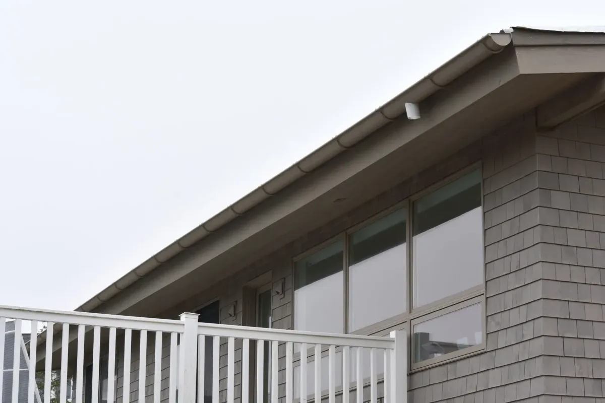 Tan half-round seamless gutter along a shingle-sided roof eave in Glassboro, NJ