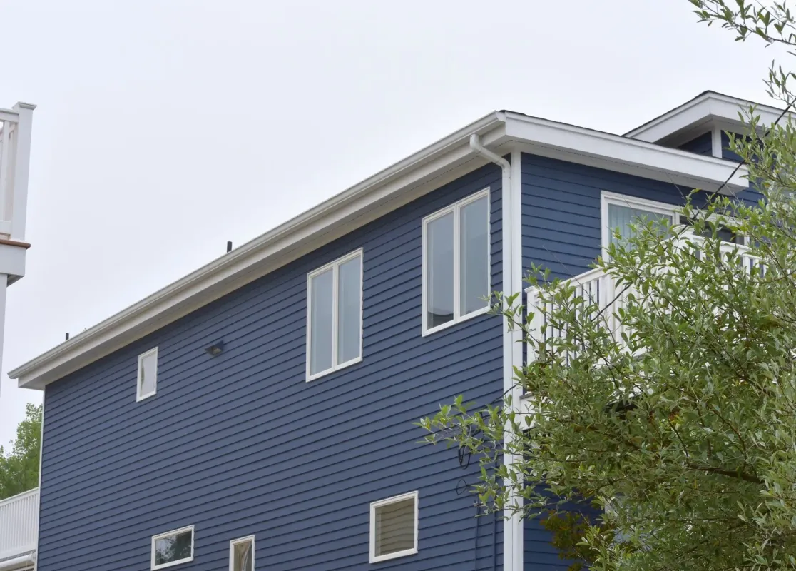 White seamless gutters wrapping the roofline of a navy blue clapboard home in Glassboro, NJ